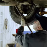 skilled-automotive-technician-checking-vehicle-undercarriage-with-pry-bar